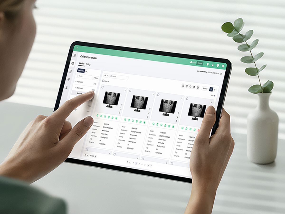Hands holding a tablet and operating a medical calibration dashboard.