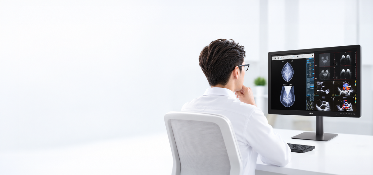 A medical professional examines diagnostic scans on a monitor.