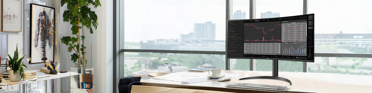 A curved LG monitor displaying financial charts sits on a desk with a keyboard, mouse, and coffee cup in front of a window showing a city view.